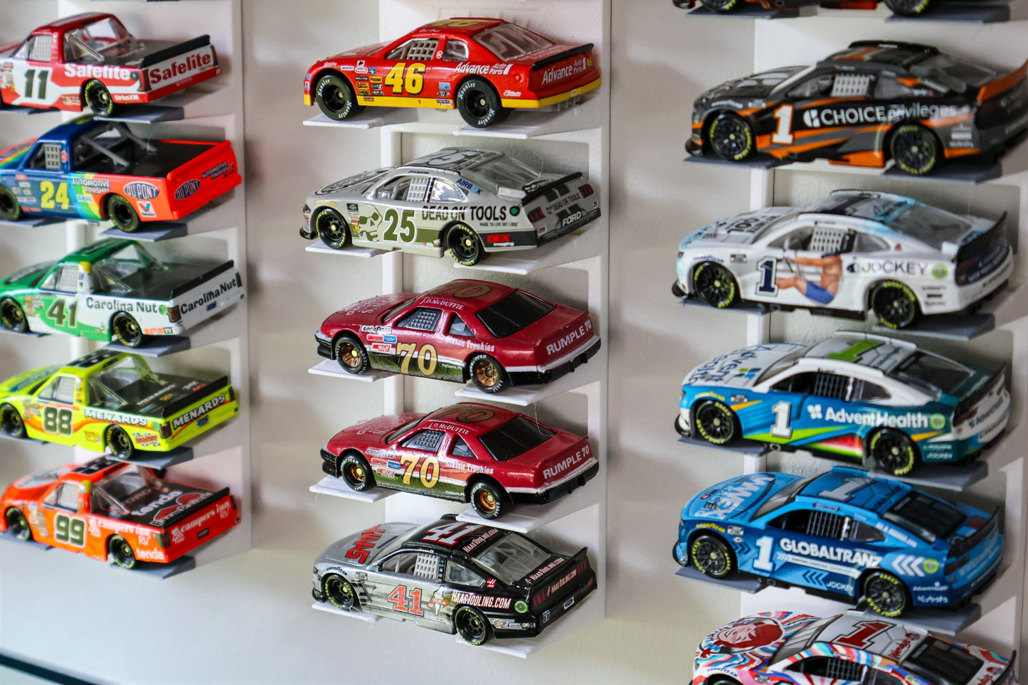 Close-up of RAM Designz 1/64 scale wall display holding NASCAR diecast cars