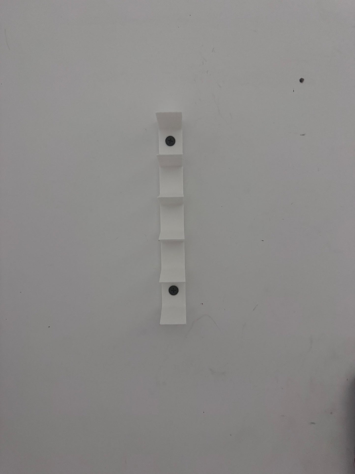 Close view of the minimalist wall-mounted diecast display and screw mounting points