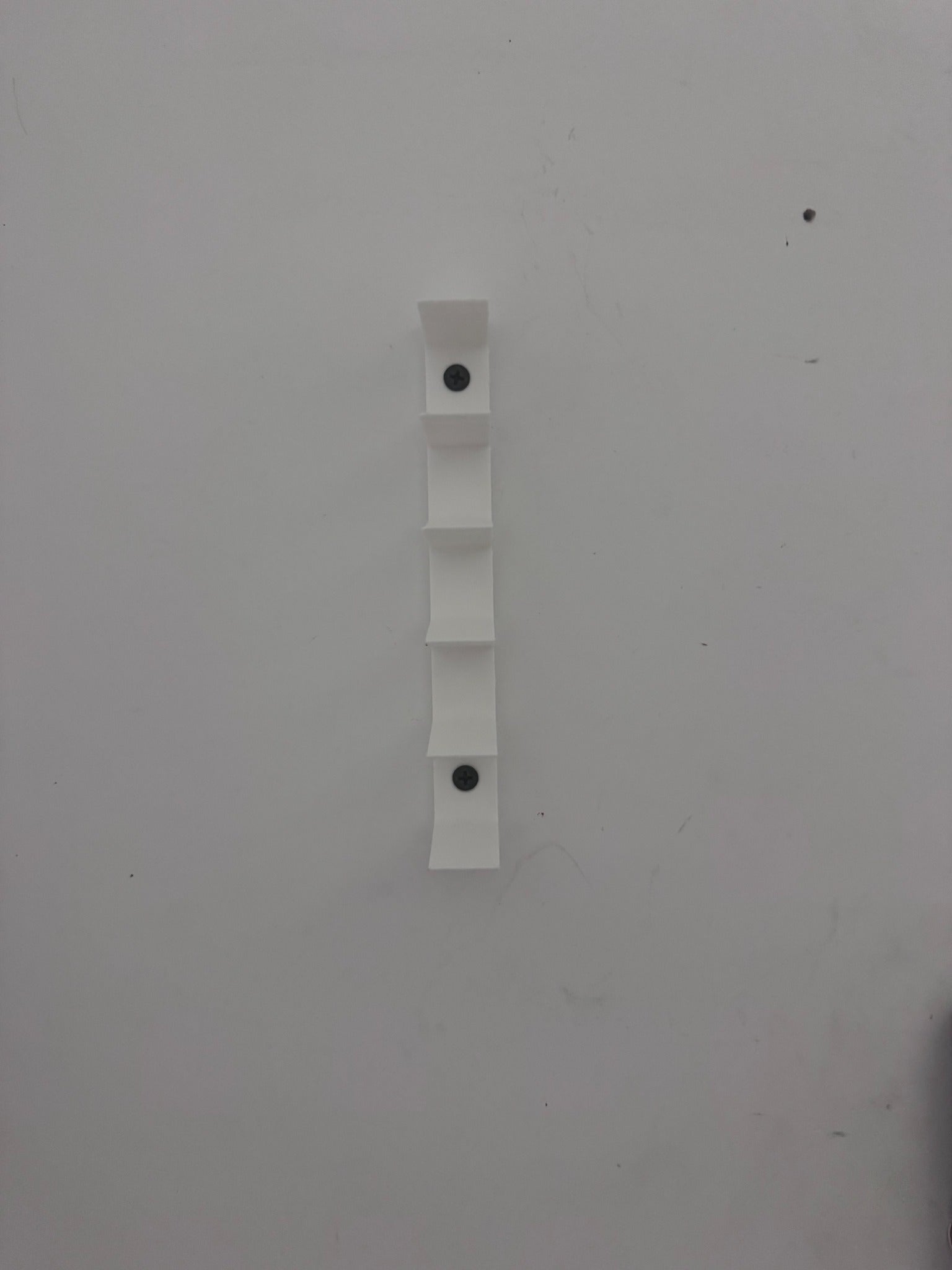 Close view of the minimalist wall-mounted diecast display and screw mounting points